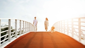 A couple walking on a bridge with their dog