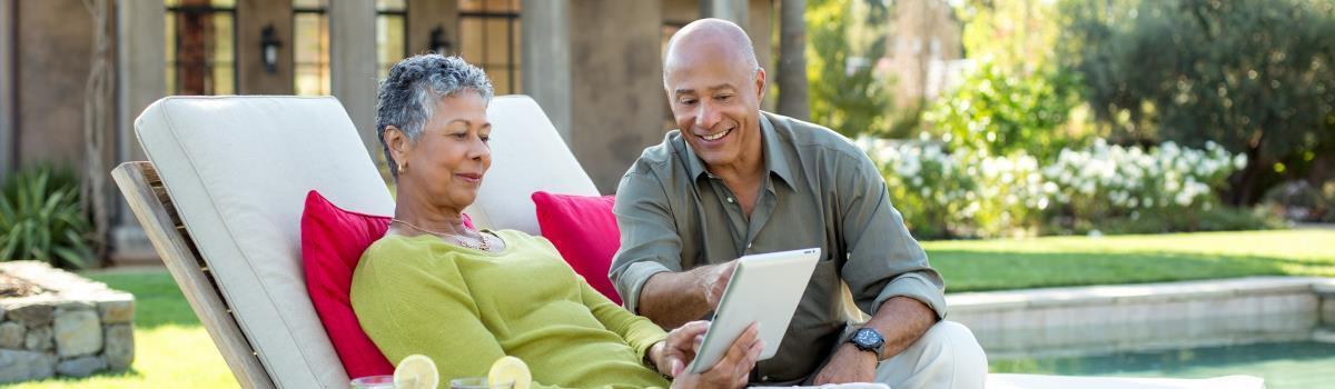 couple reviewing tablet together by pool