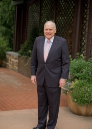 white man standing in black suit standing in front of fence