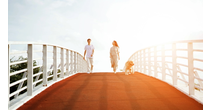 A couple walking on a bridge with their dog