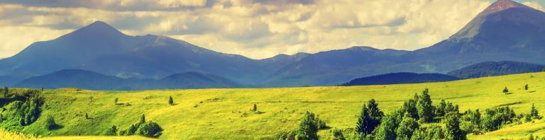 green hills with mountains in the background