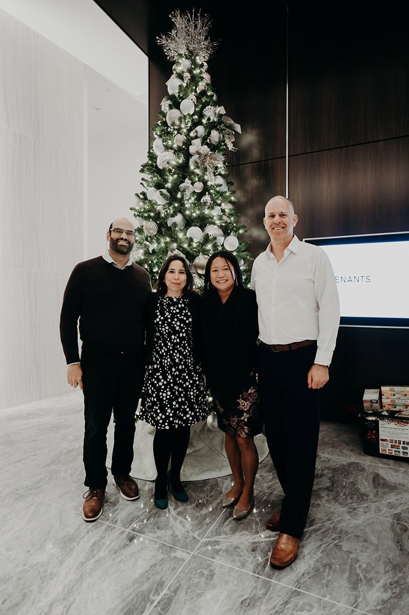 4 clients smiling infront of a christmas tree