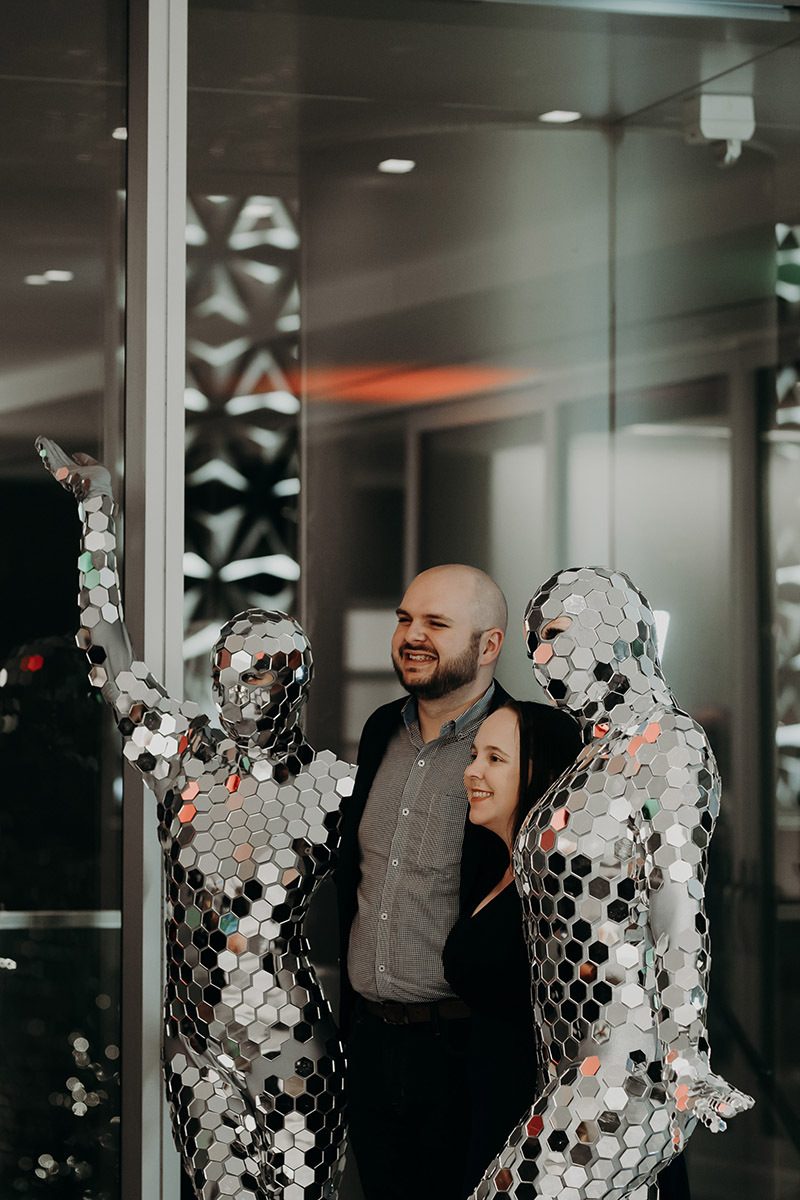 2 clients posing for a photo with 2 people dressed in silver mirror outfits