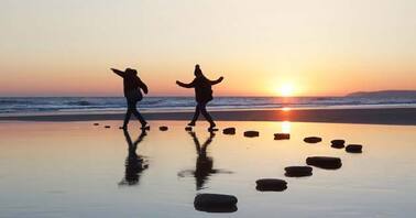 two people on a beach at sunset