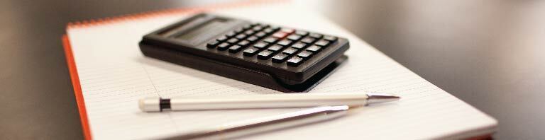 calculator, pen, and papers on desk