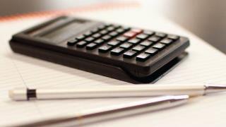 calculator, pen, and papers on desk